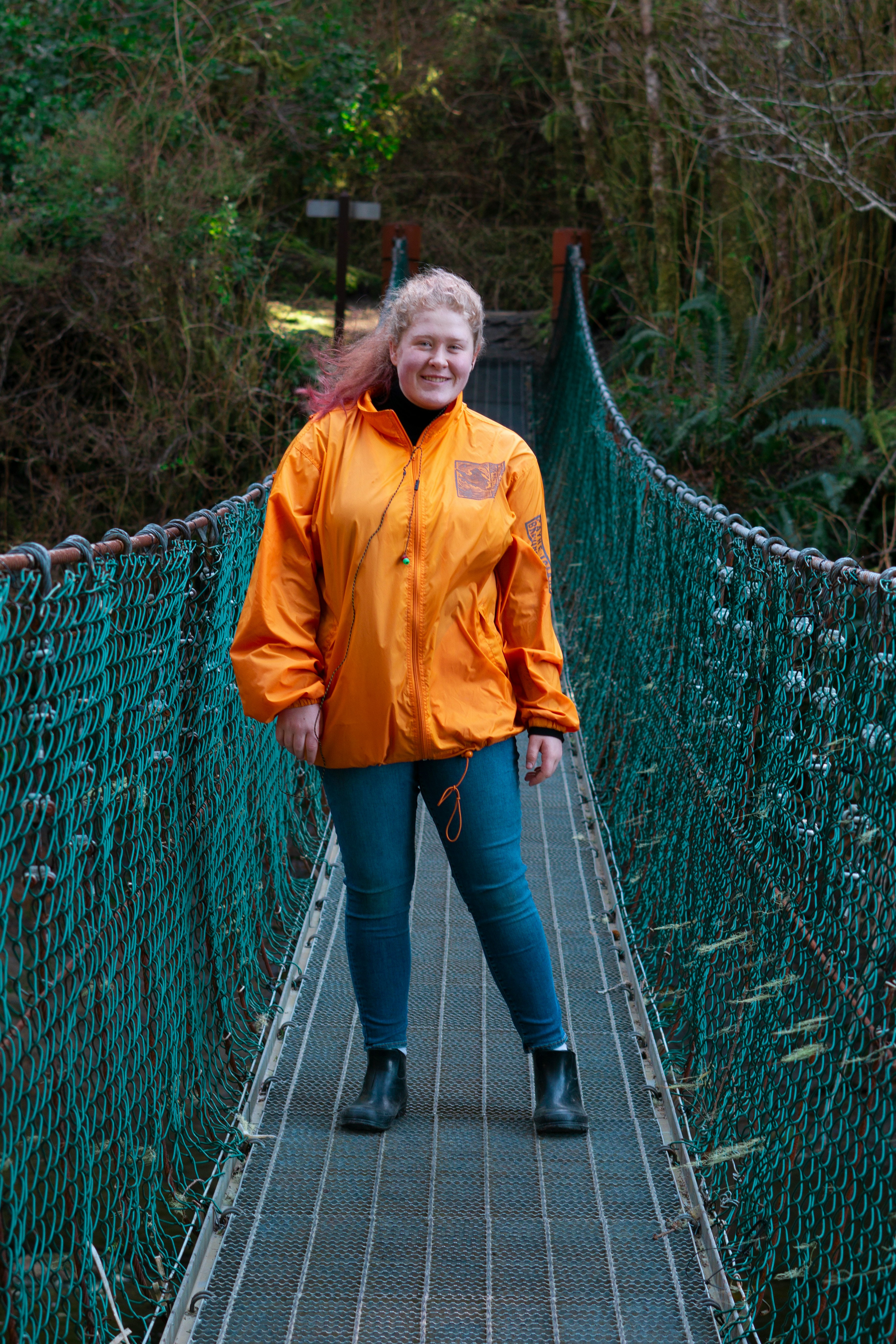 woman in yellow jacket standing on hanging bridge